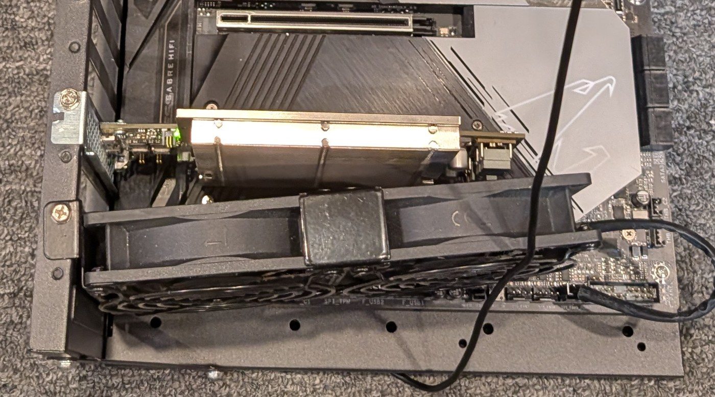 aifoundry2's open frame before the swap: the ET card's heat-pipe plate, and below it a 120 mm fan held in a black clip.
