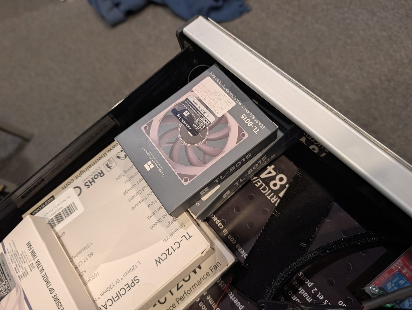 A drawer of boxed spare fans: Thermalright TL-8015 80 mm slim fans and a TL-C12CW 120 mm fan.